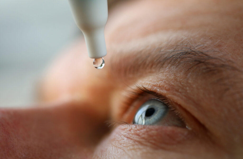 A close-up of an eye drop bottle near a person's eye.