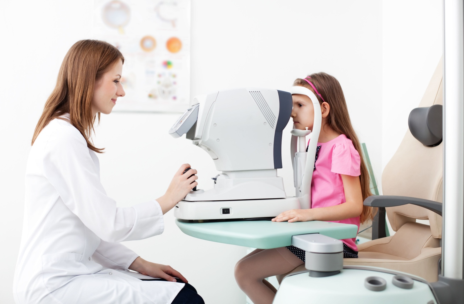 A female optometrist using a medical device to examine the eyes of a child patient and look for potential eye problems.