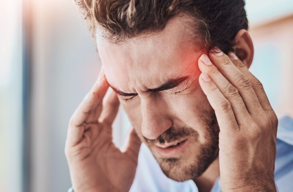 A person is struggling with headaches, that may have been triggered by dry eye symptoms.