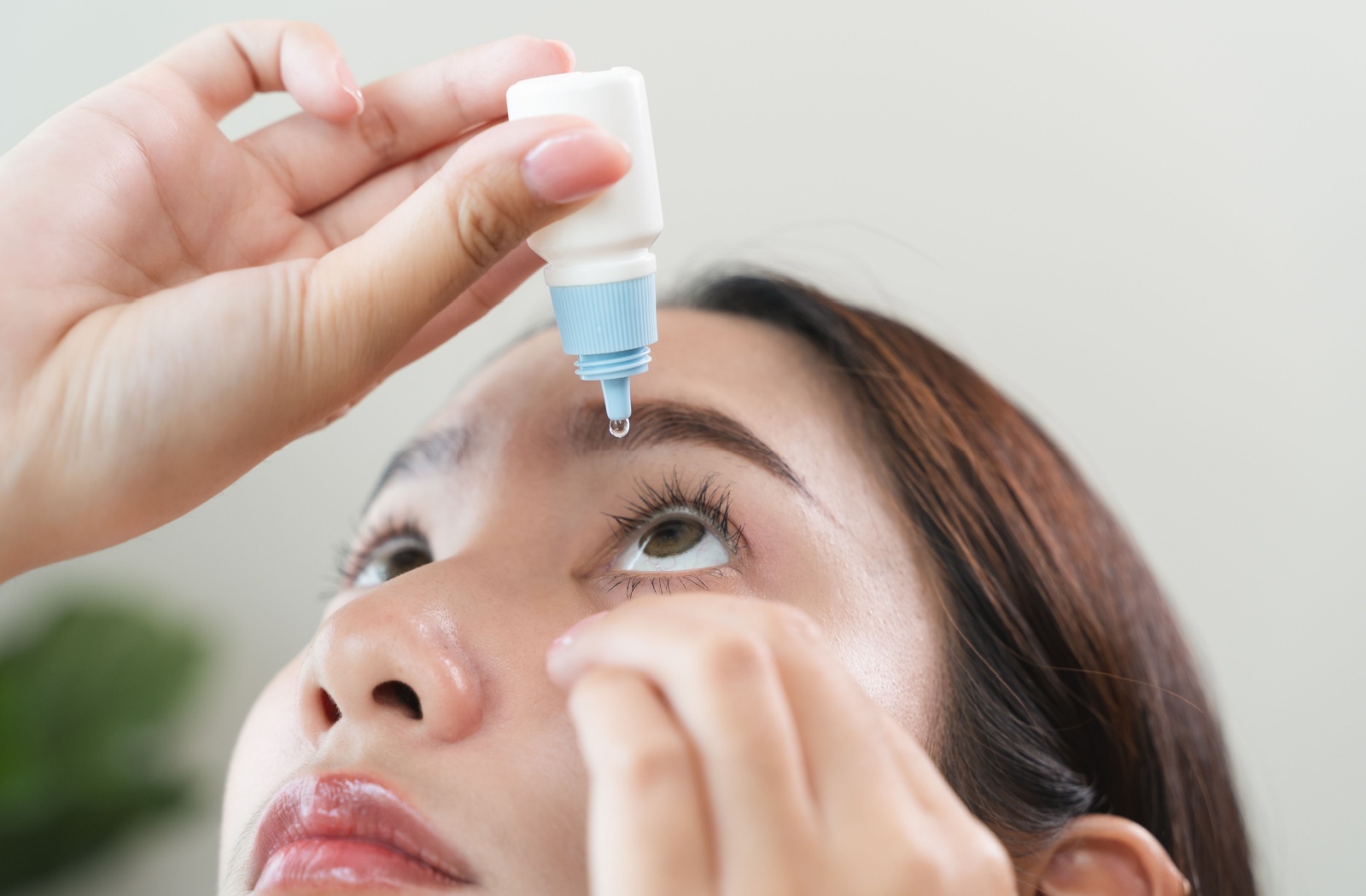 A person is placing eye drops to relieve dry eye symptoms.