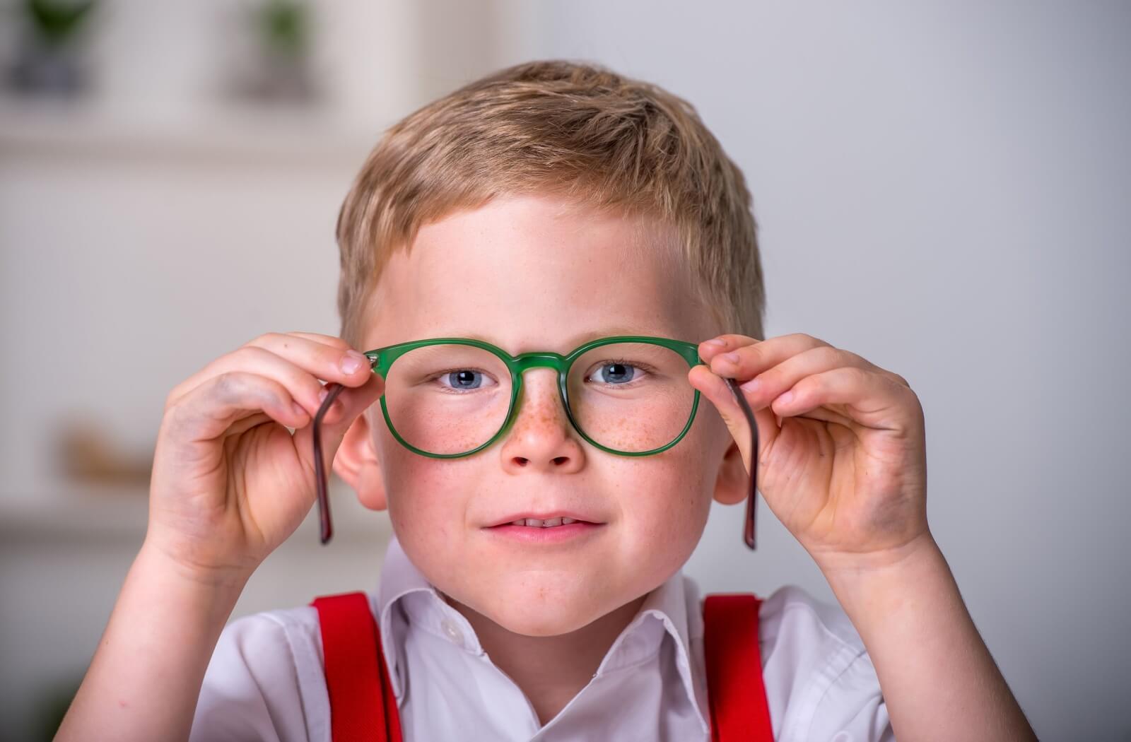 Young boy wearing green glasses, highlighting the importance of vision correction for managing myopia in children.